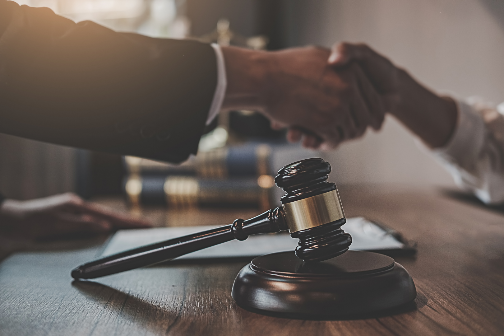 Scope out The Felty Legal Brief Blog. Handshake over a judge’s gavel on a desk in a courtroom setting