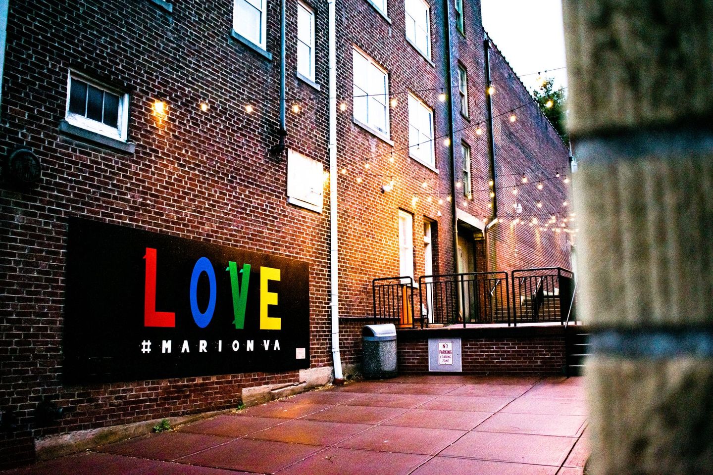 Brick alley with colorful “LOVE” mural sign on a black wall beside a brick building in Marion Virginia.