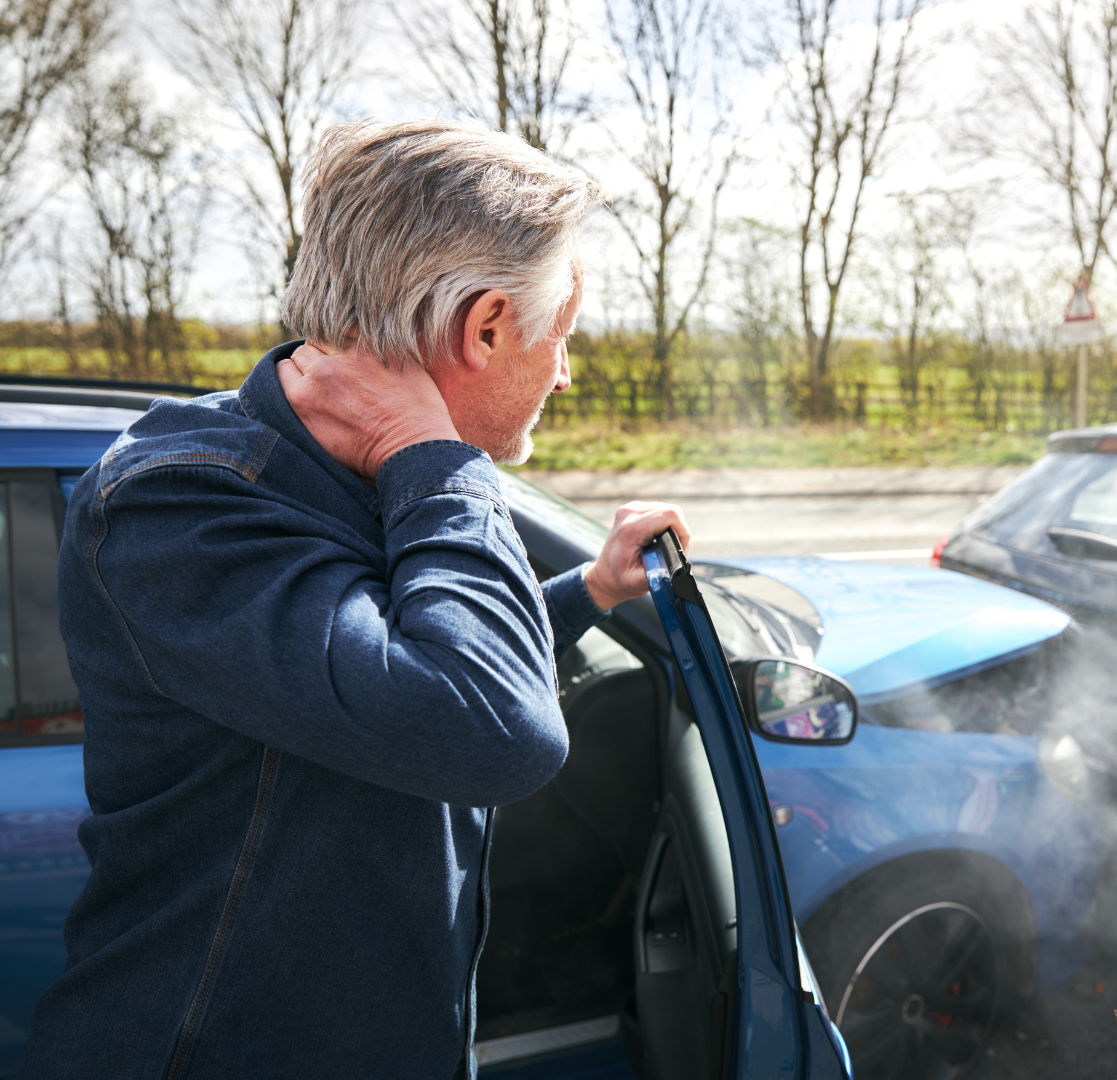 Person holding a car door while coughing beside a blue car outdoors