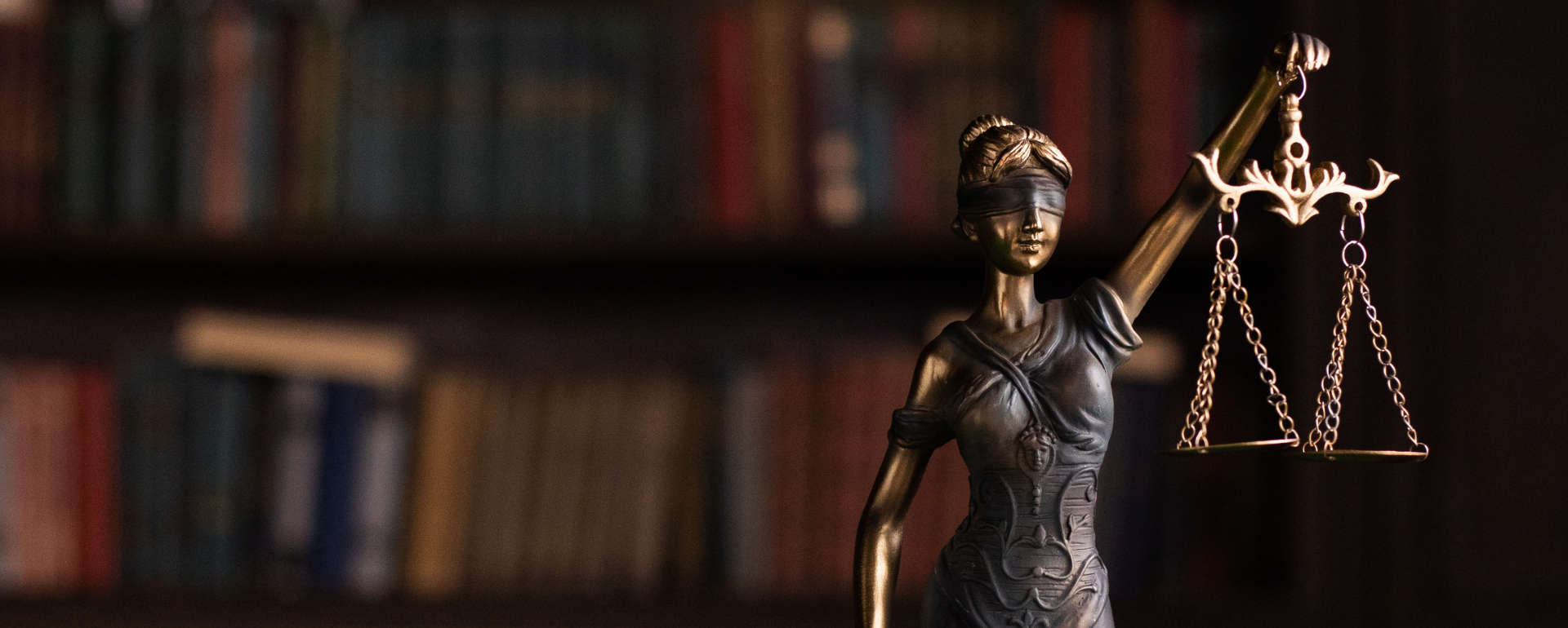View our Service Area Statue of Justice with scales in front of blurred law books