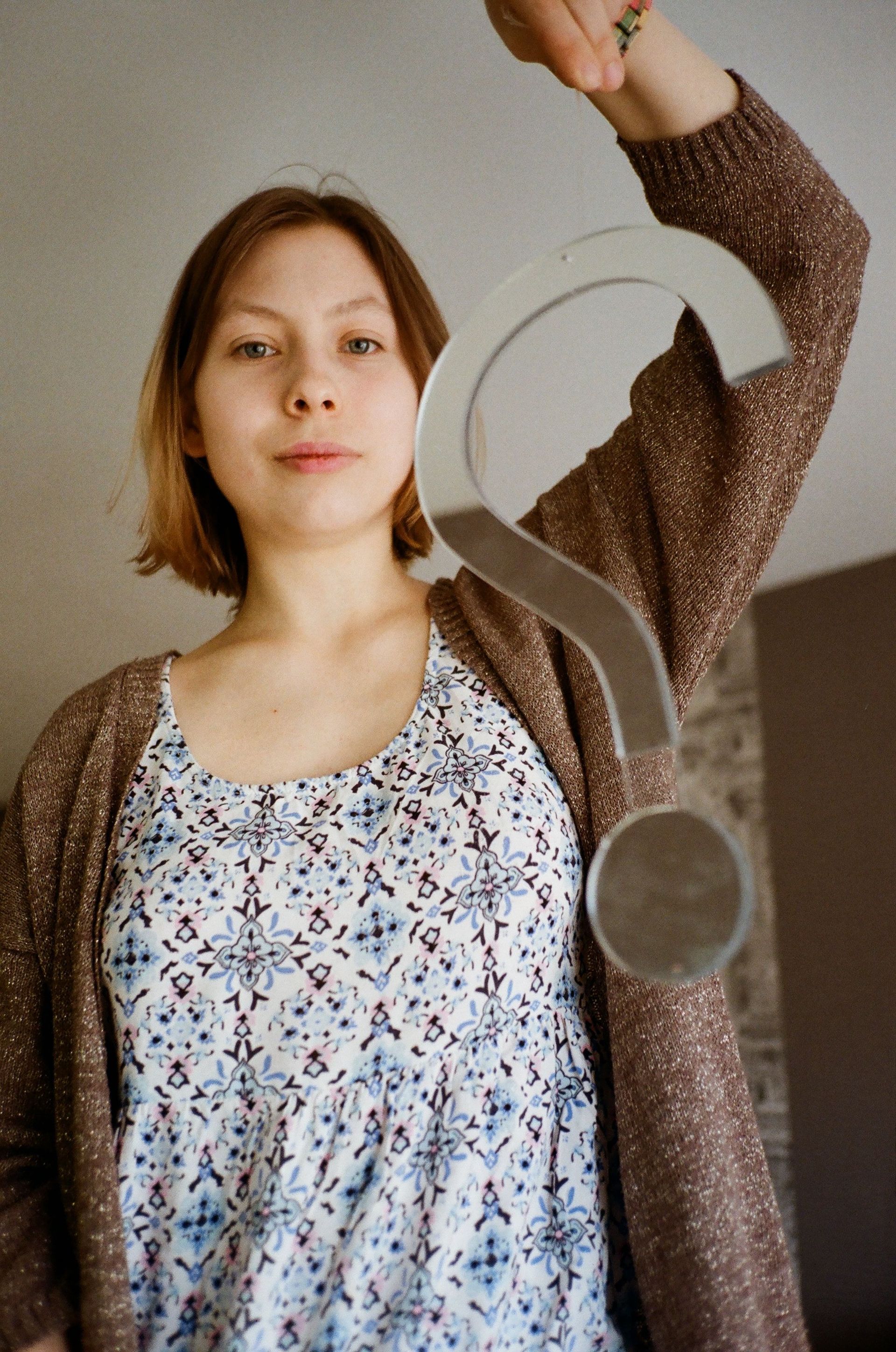 Get more answers at our FAQ page. Woman holding a large gray question mark-shaped sign indoors