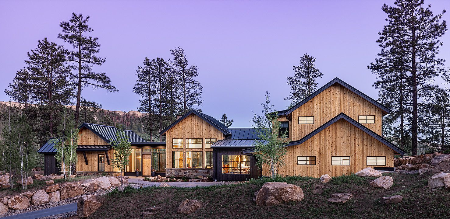 A group of wooden houses are sitting on top of a hill surrounded by trees.