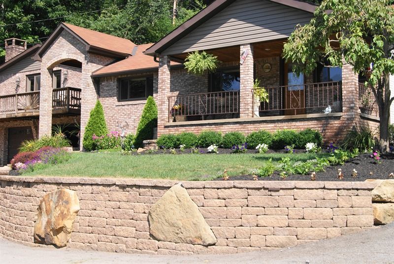 House with brick facade, lawn, and retaining wall.