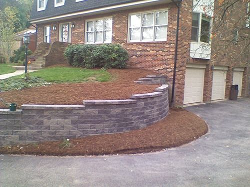 Brick house with a retaining wall and driveway.