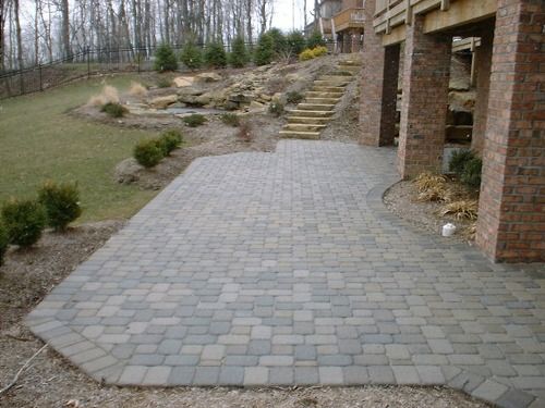 Brick patio with bordering brick columns and steps leading up to yard.
