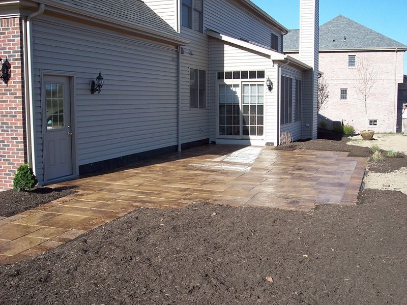 Paver patio next to a house with a back door and sliding glass door.