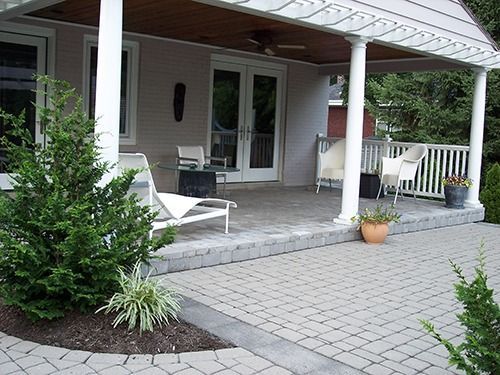 Patio with gray pavers, white chairs, and a covered pergola.