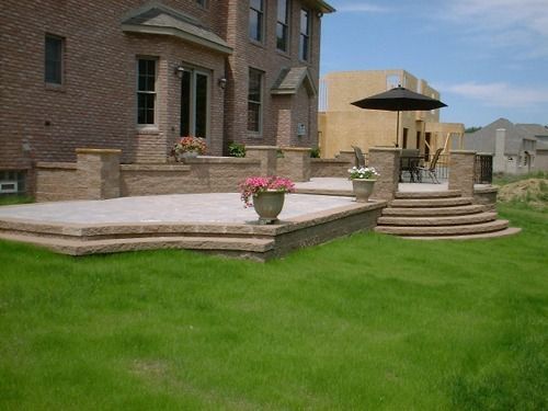 Brick house with patio made of tan pavers and decorative planters.