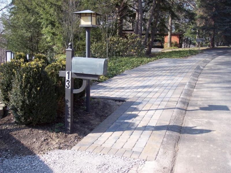 Mailbox with street number 13, next to a brick walkway and gravel area.