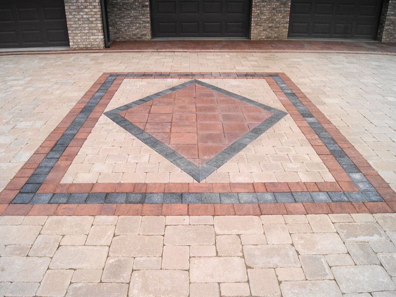 Brick driveway with a decorative diamond pattern in shades of beige, red, and gray.