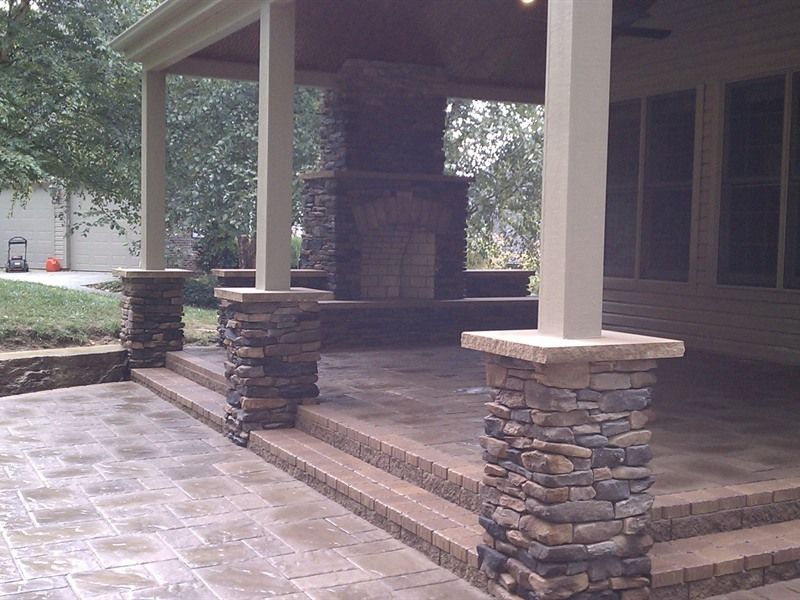 Stone patio with steps, pillars, fireplace, and covered seating area.
