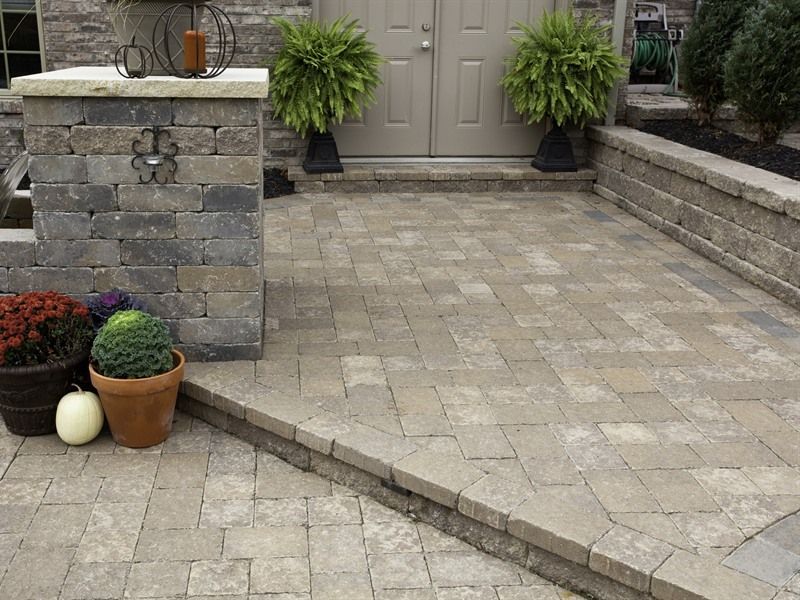 Brick patio with steps, planters, and front door, in a neutral color palette.