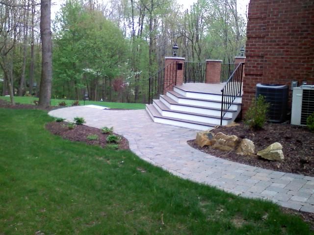 Stone path leads to outdoor steps, lawn on the left, building on the right.