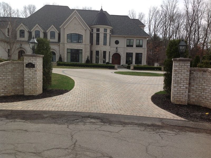 Large brick home with circular brick driveway; entrance pillars and manicured landscaping.
