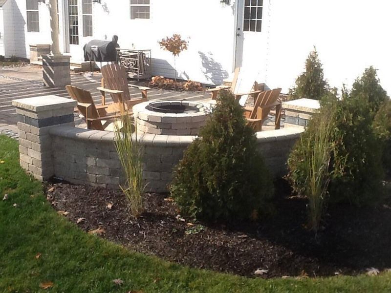 Backyard patio with fire pit, Adirondack chairs, and landscaping.