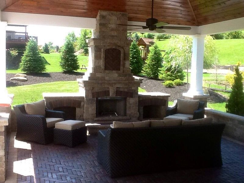Covered outdoor patio with stone fireplace and seating.