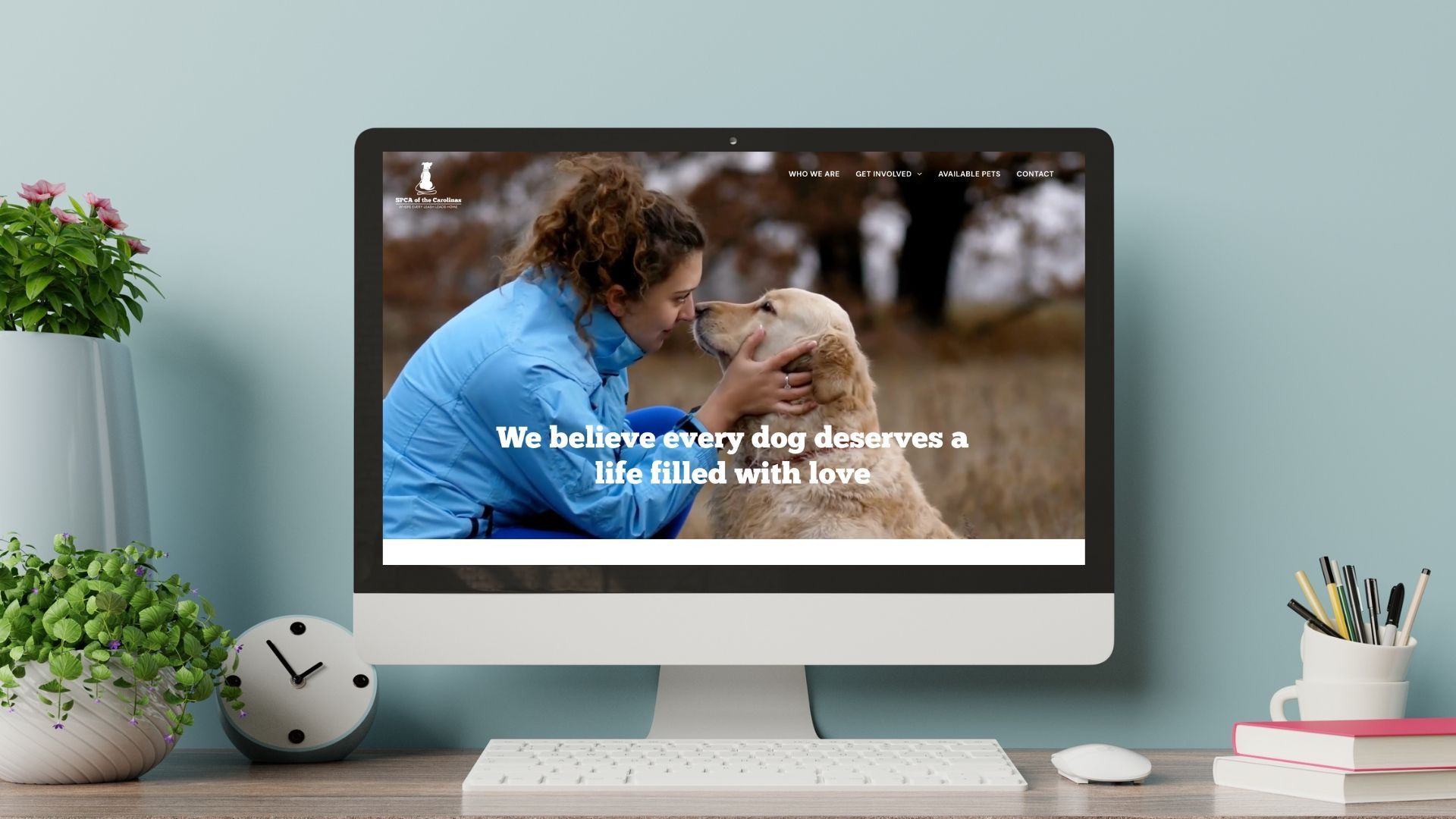 A computer screen shows a woman petting a dog on a desk.
