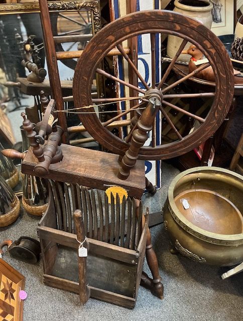 A wooden spinning wheel sits on top of a wooden stool