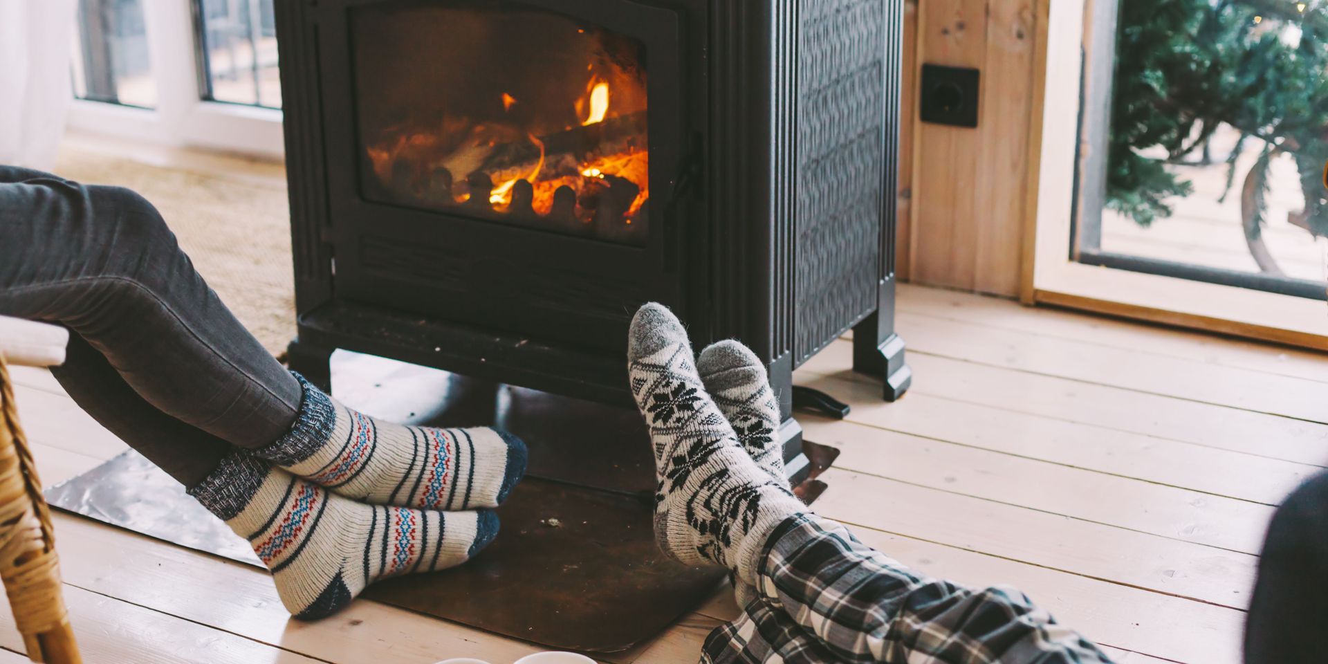 A person is laying on the floor with their feet up in front of a fireplace.