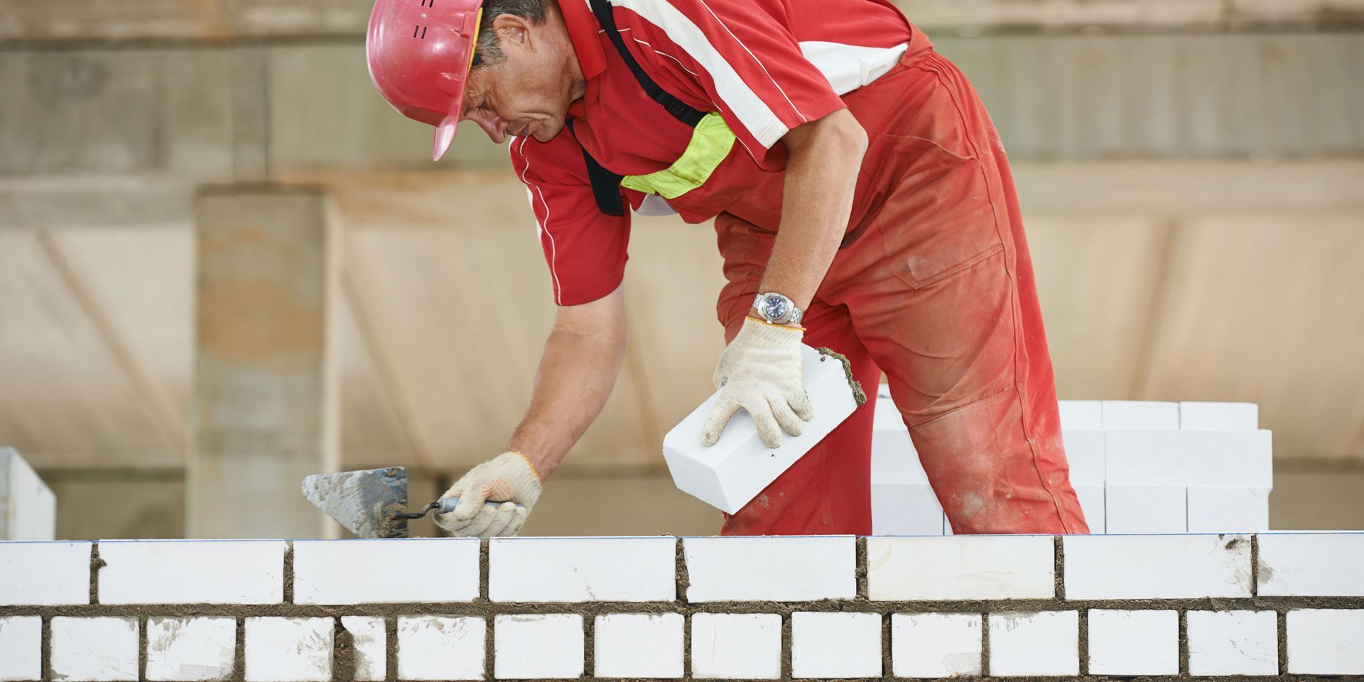 Construction worker laying bricks and mortar delivering durable commercial building solutions