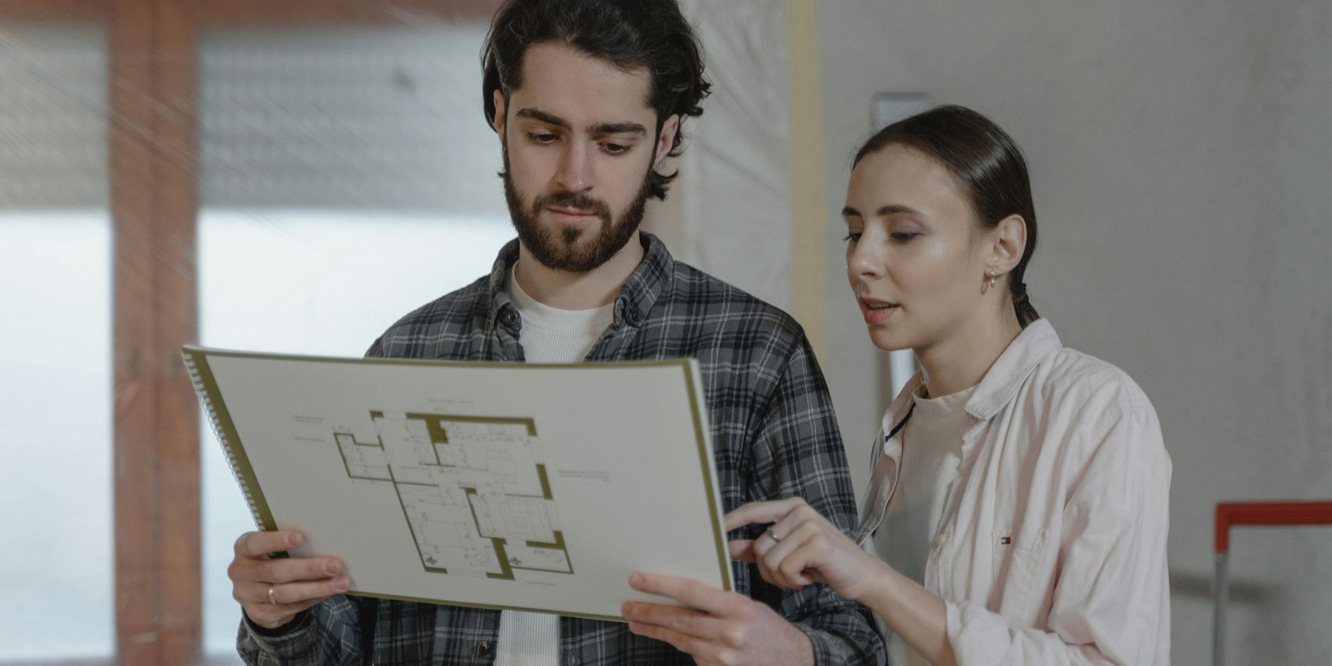 Clients reviewing architectural plans with a consultant during a building solutions project planning phase