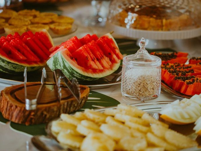 Buffet de café da manhã: melancia, abacaxi, mamão e doces.