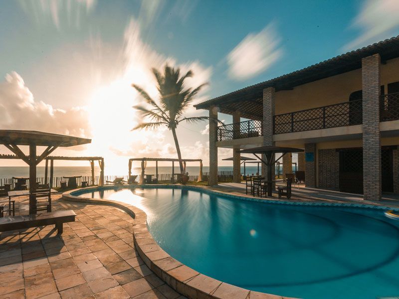 Resort à beira da piscina com vista para o mar sob um céu ensolarado.