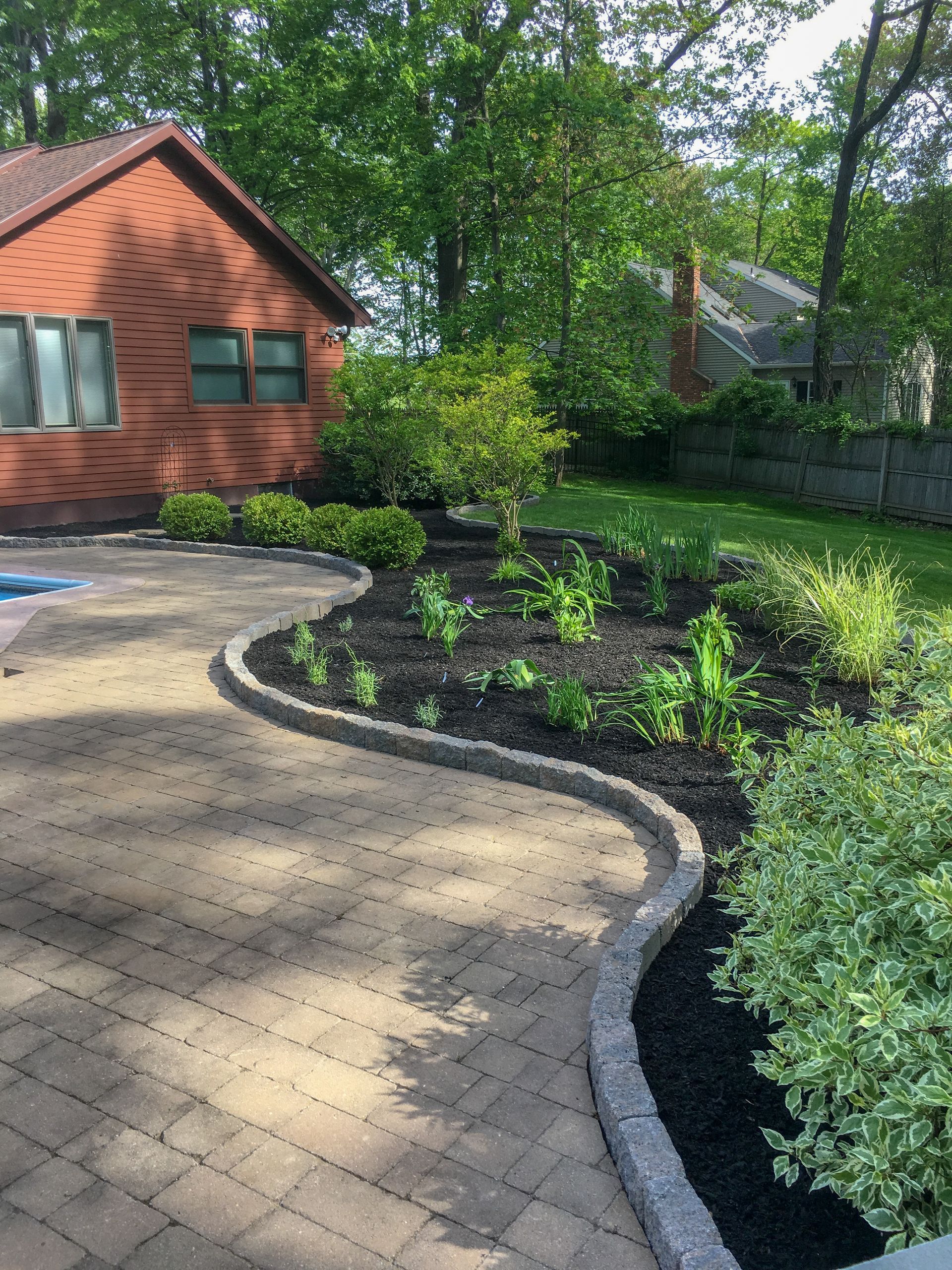 A brick walkway leading to a house with a swimming pool in the backyard.