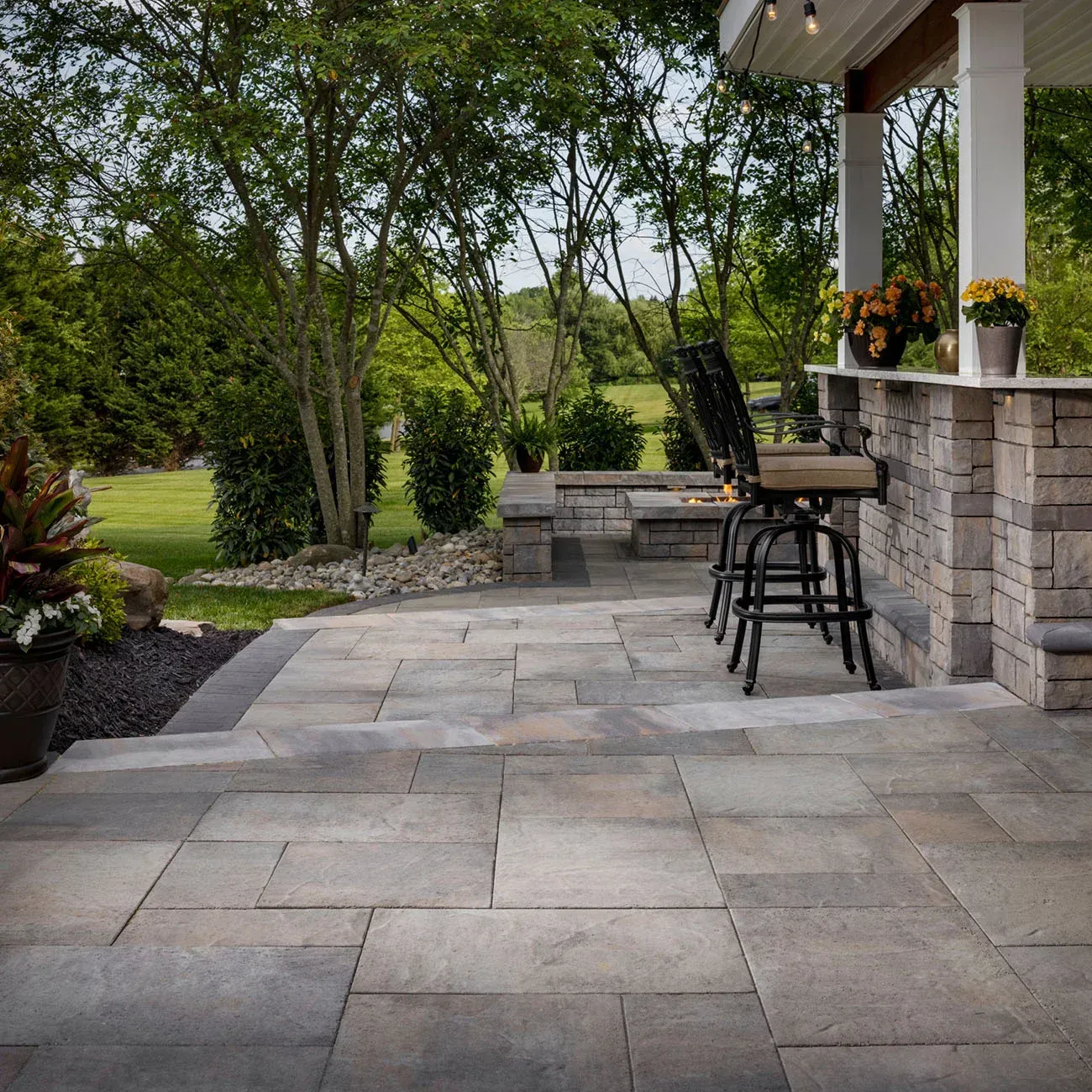 A patio with a bar and chairs and trees in the background