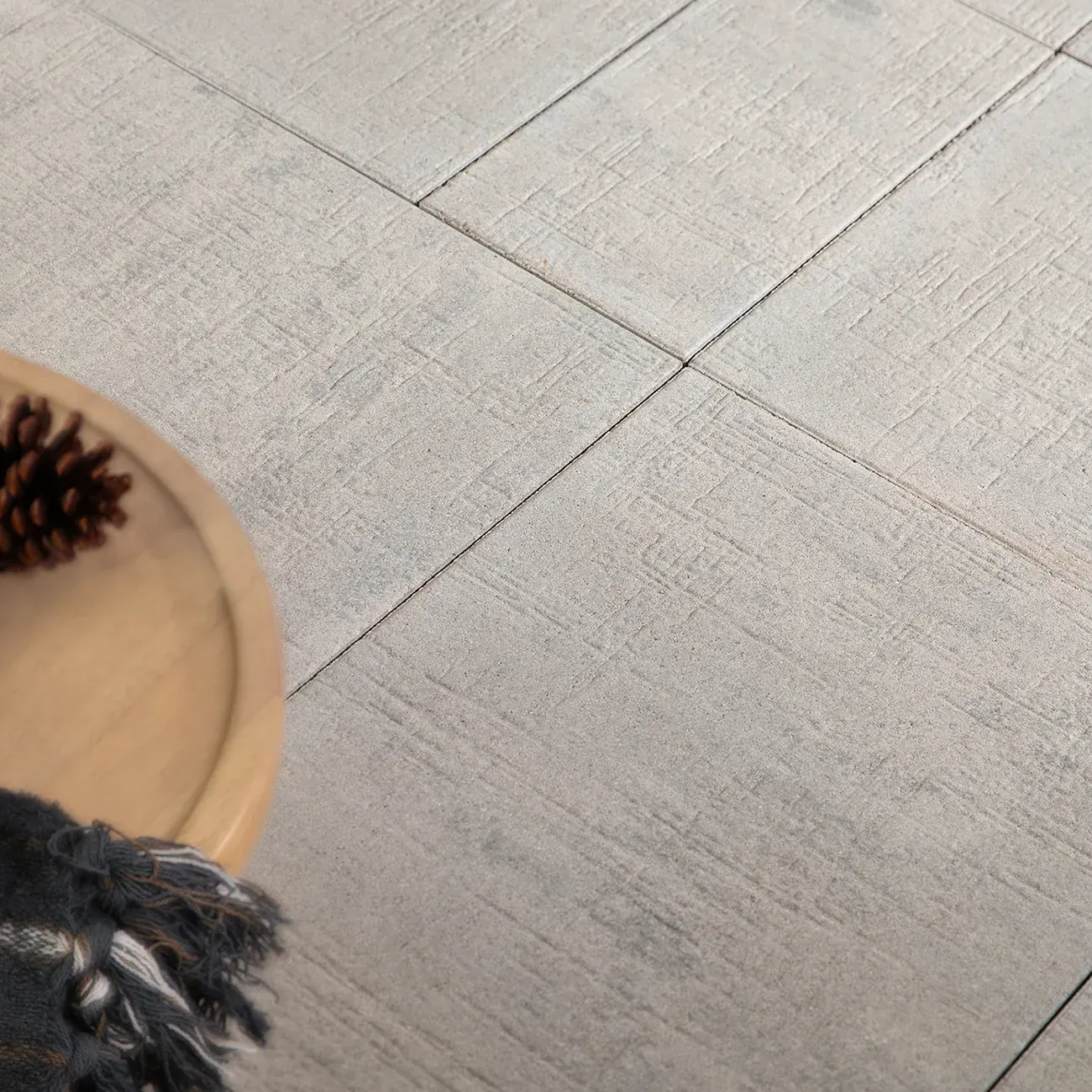 A table with a pine cone on top of it on a tiled floor.