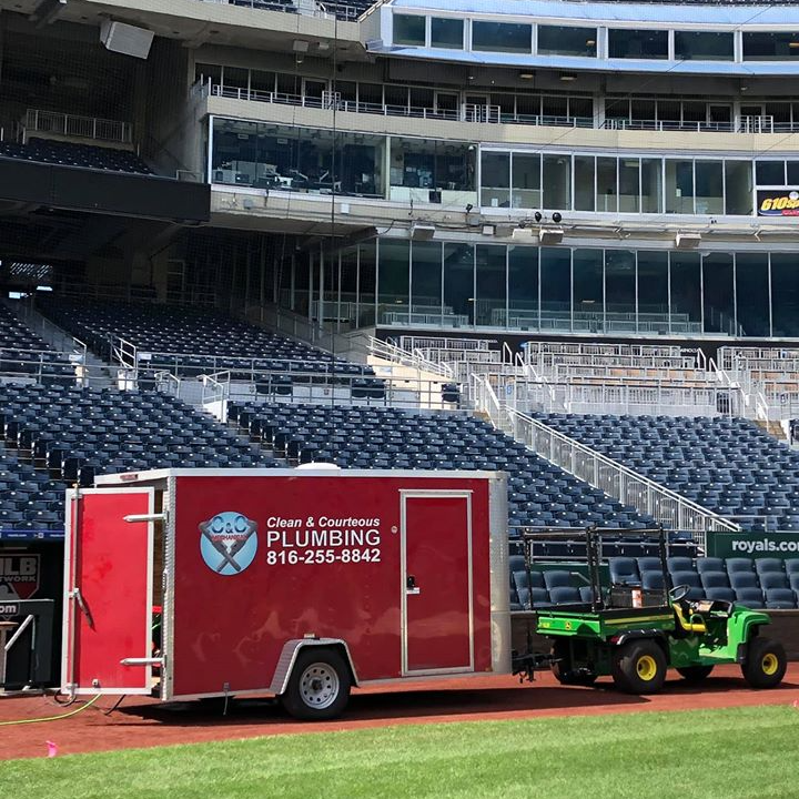 A plumbing trailer is parked in front of a stadium