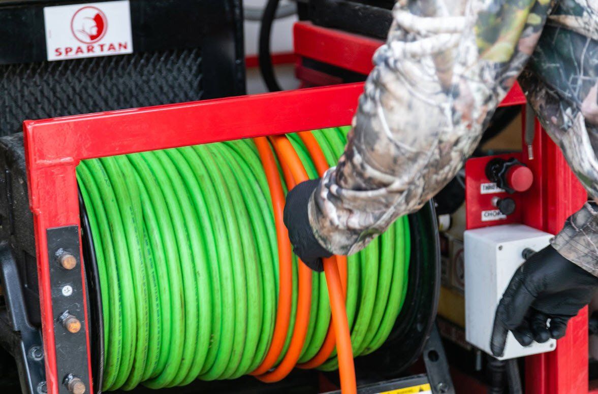 A person is holding a green and orange hose on a machine.