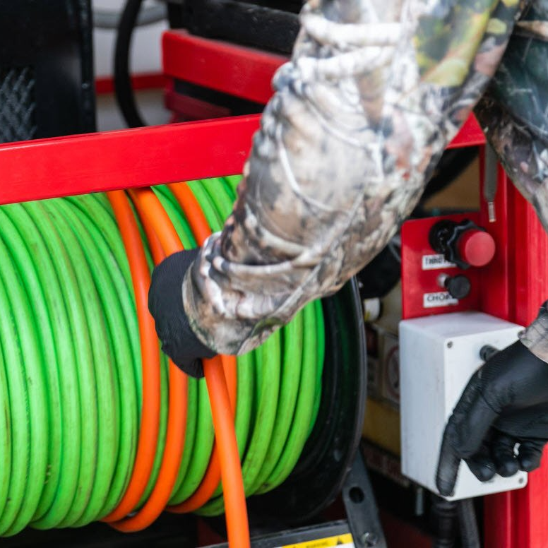 A person is holding a green and orange hose in their hand.