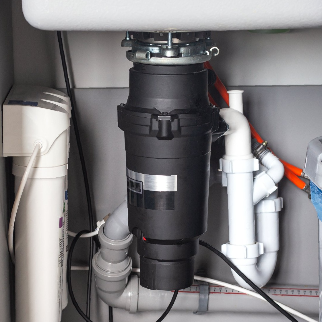 A garbage disposal is under a sink in a kitchen
