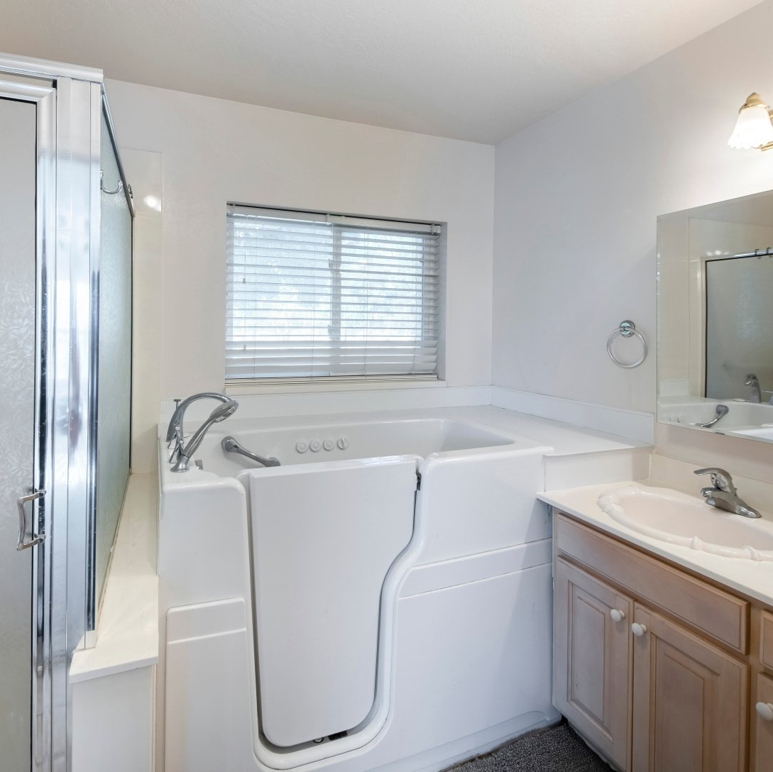 A bathroom with a walk in tub and a sink