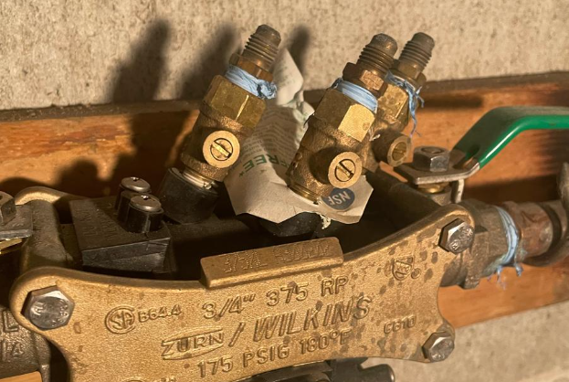 A close up of a valve on a wall with a green handle.