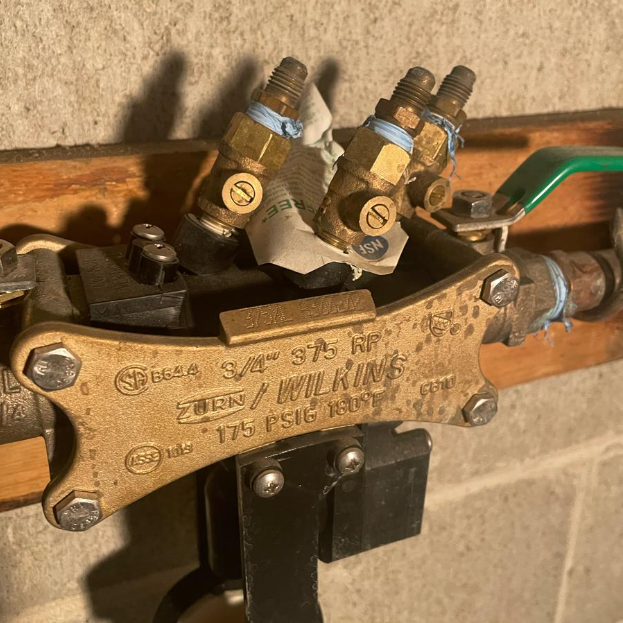 A close up of a valve on a wall with a green handle.