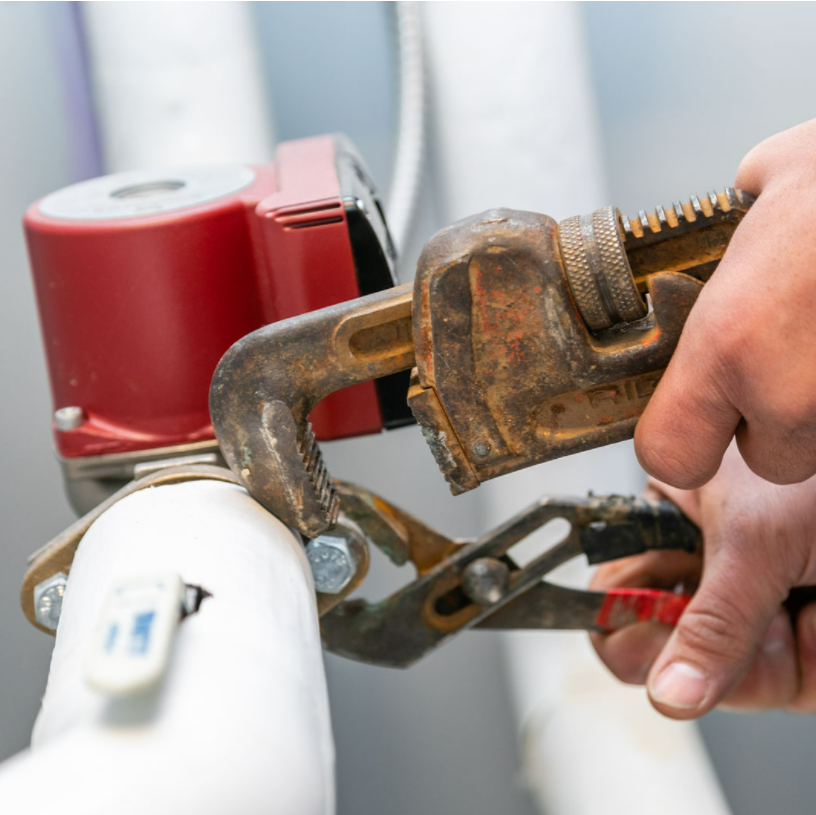 A person is working on a pipe with a wrench.