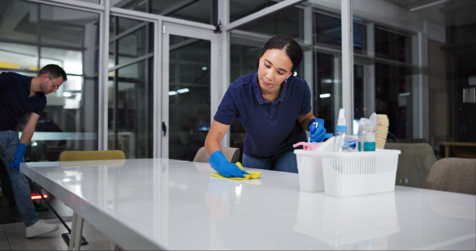 Two people cleaning carpet in an office space. One kneels giving a thumbs up, the other operates a floor cleaning machine, both smiling. Two people cleaning carpet in an office space. One kneels giving a thumbs up, the other operates a floor cleaning machine, both smiling.