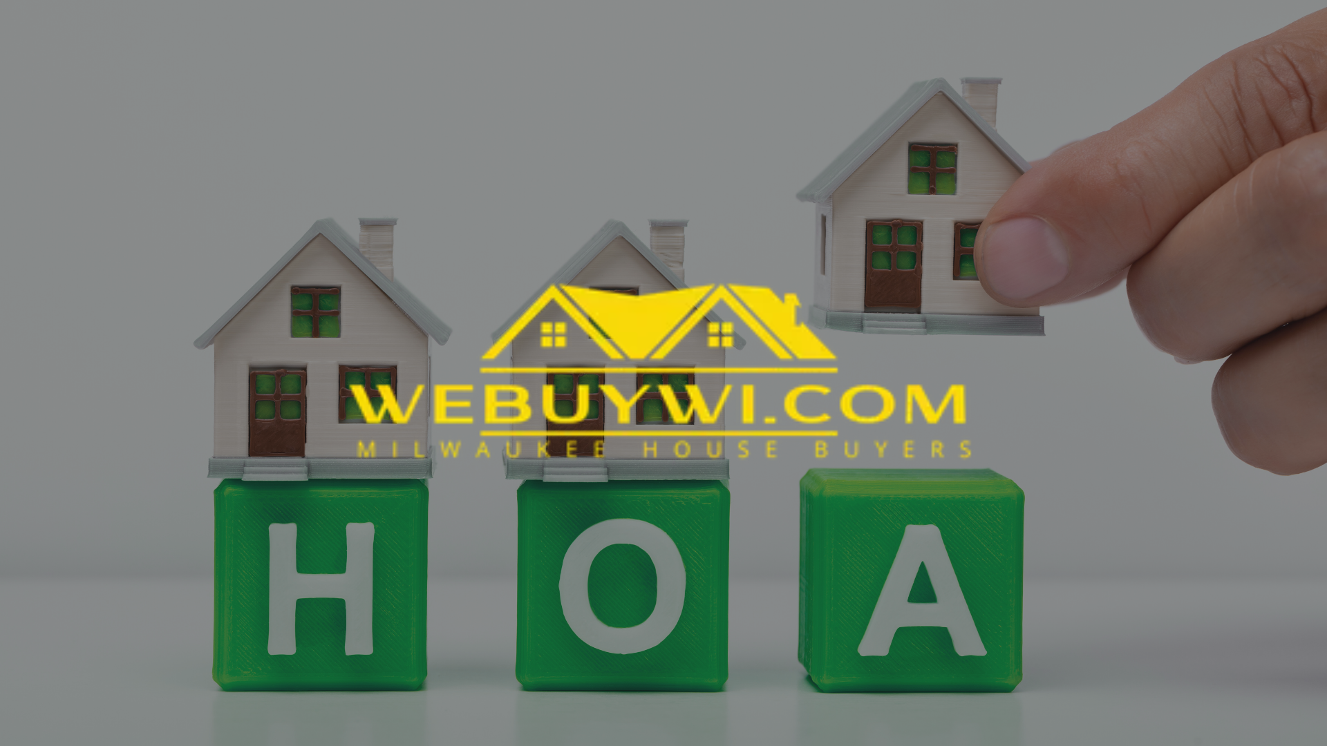 Hand placing toy house on green blocks spelling