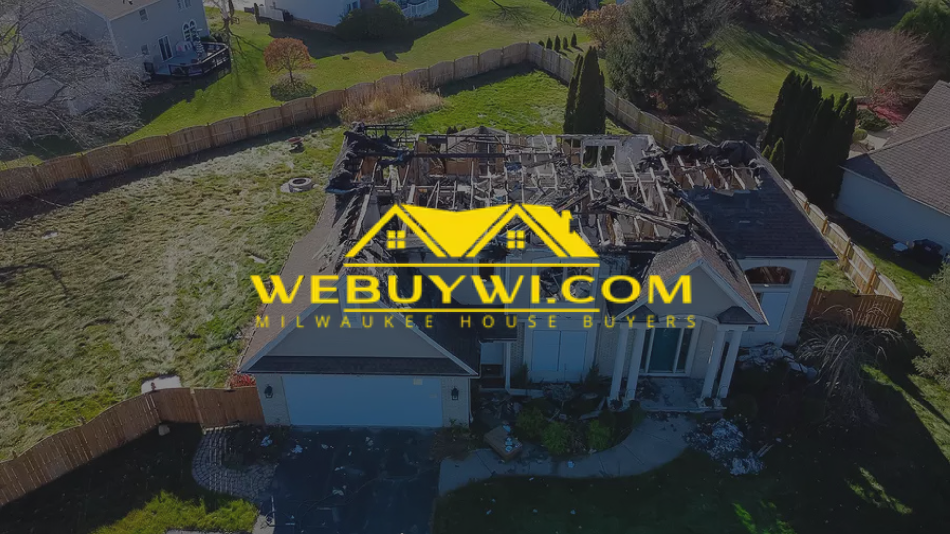 An aerial view shows a house with a severely damaged roof, likely from a fire, with a