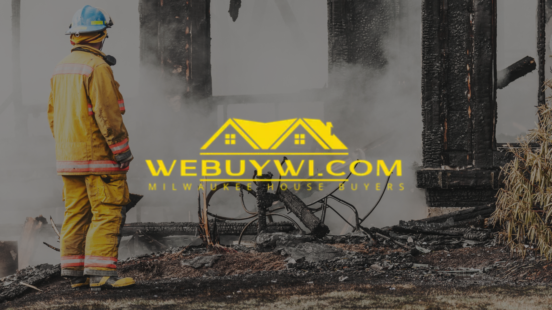 Firefighter in yellow gear surveys a fire-damaged building,