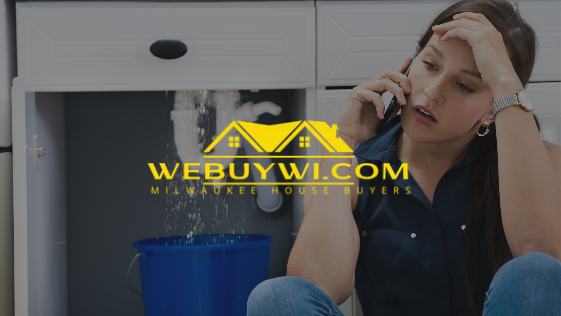 Woman on phone, stressed, near a leaking pipe under a kitchen sink. Blue bucket collects water. Logo: