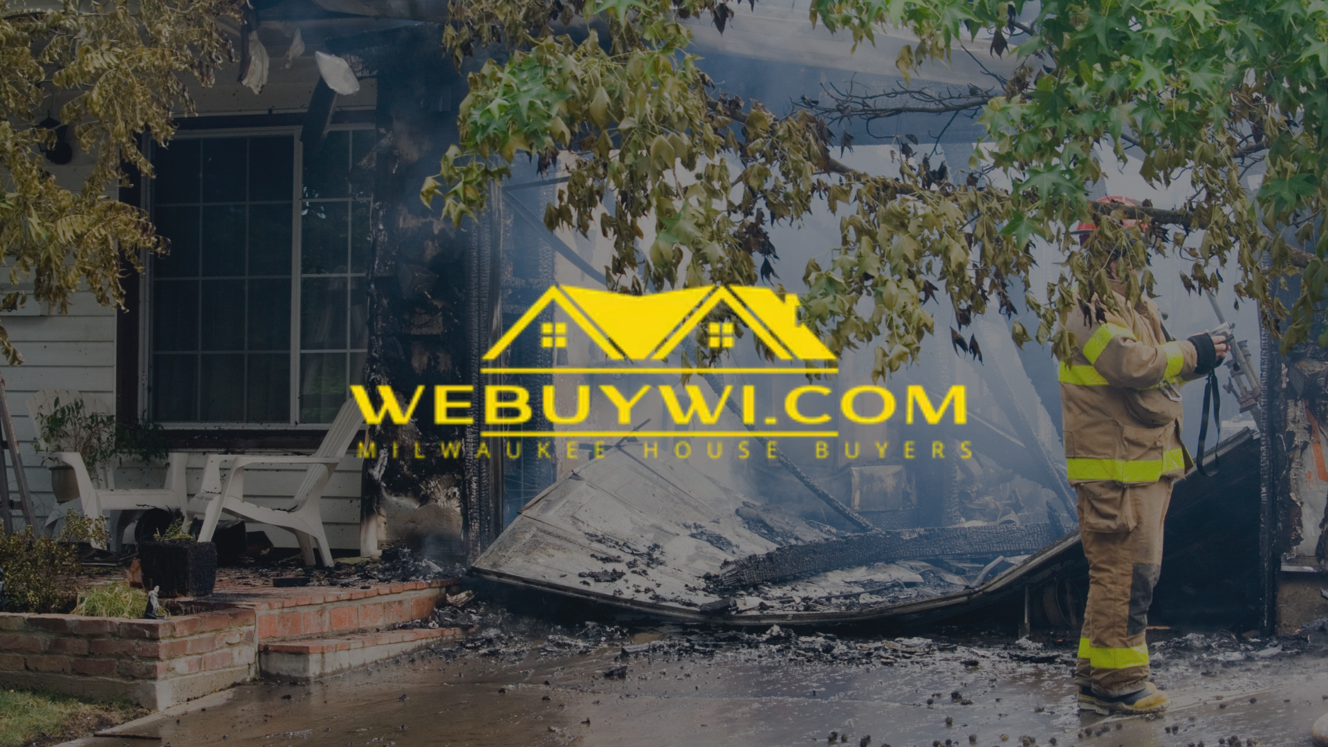 A firefighter surveys fire damage at a house with a damaged roof. Logo: