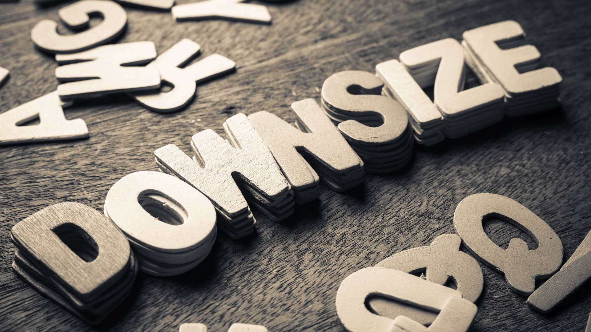3D white “DOWNSIZE” letters on a dark textured surface, with scattered letters around it.