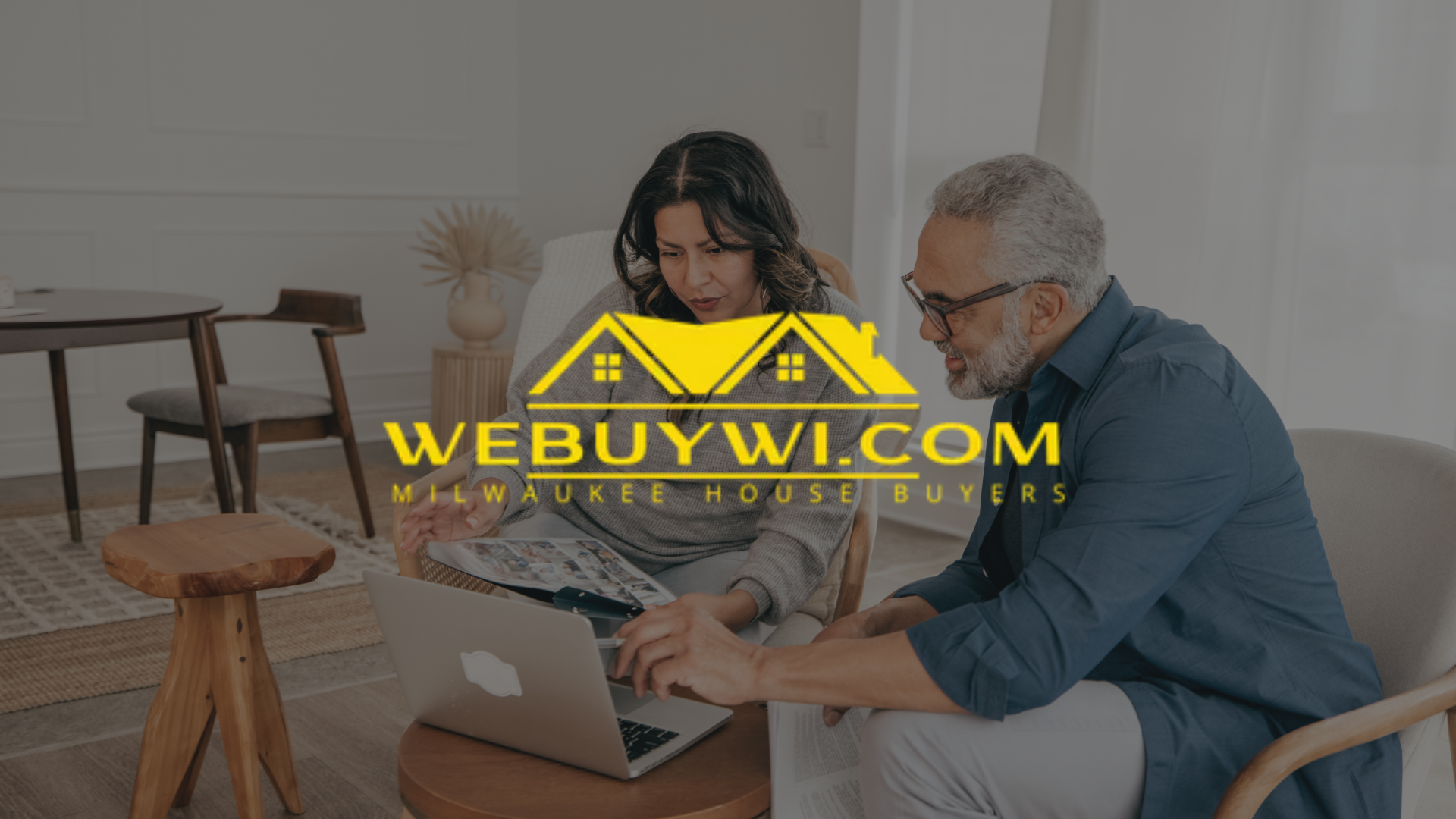 Two people looking at a laptop indoors with the logo
