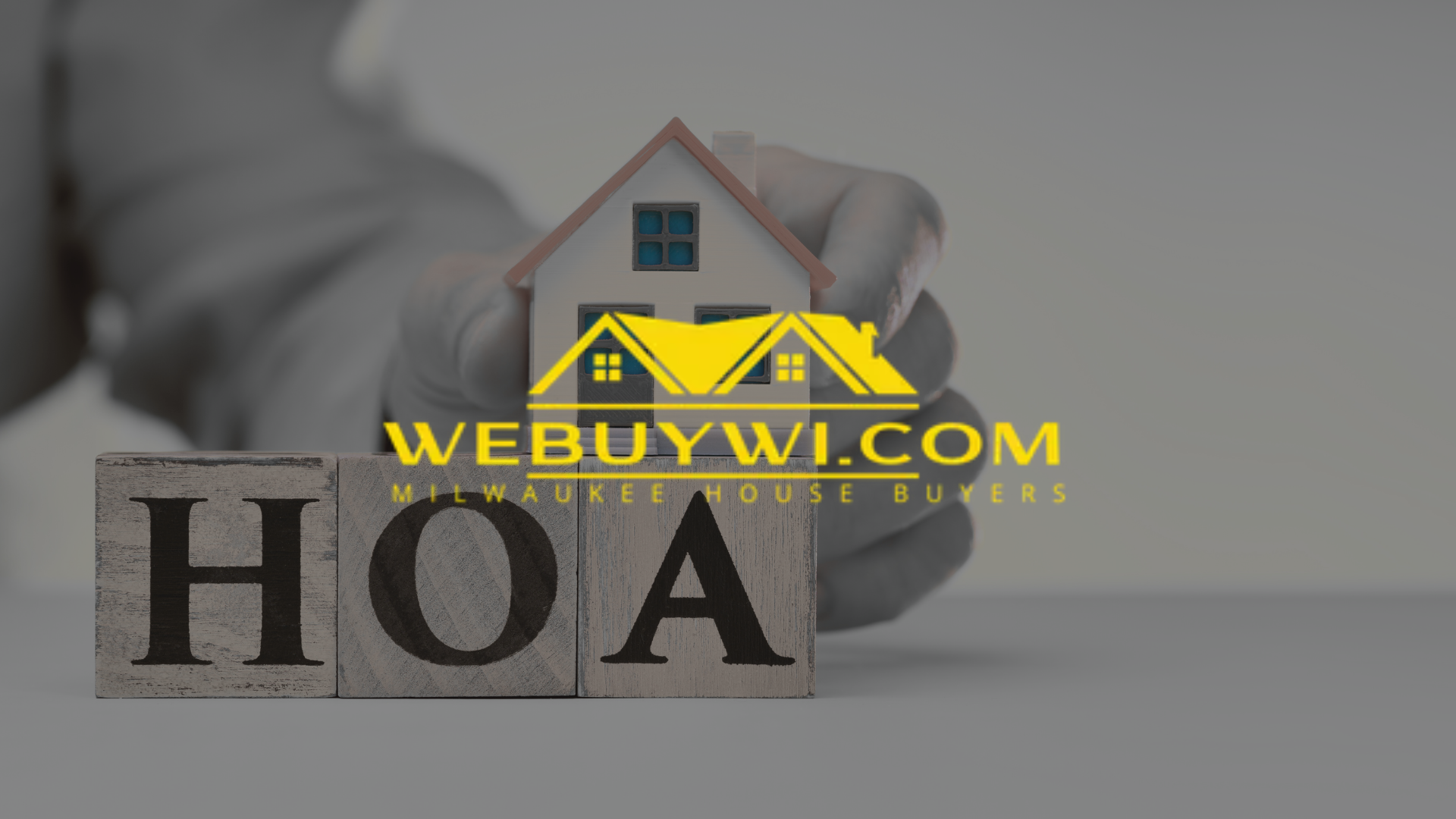 Hand holding model house above wooden blocks spelling