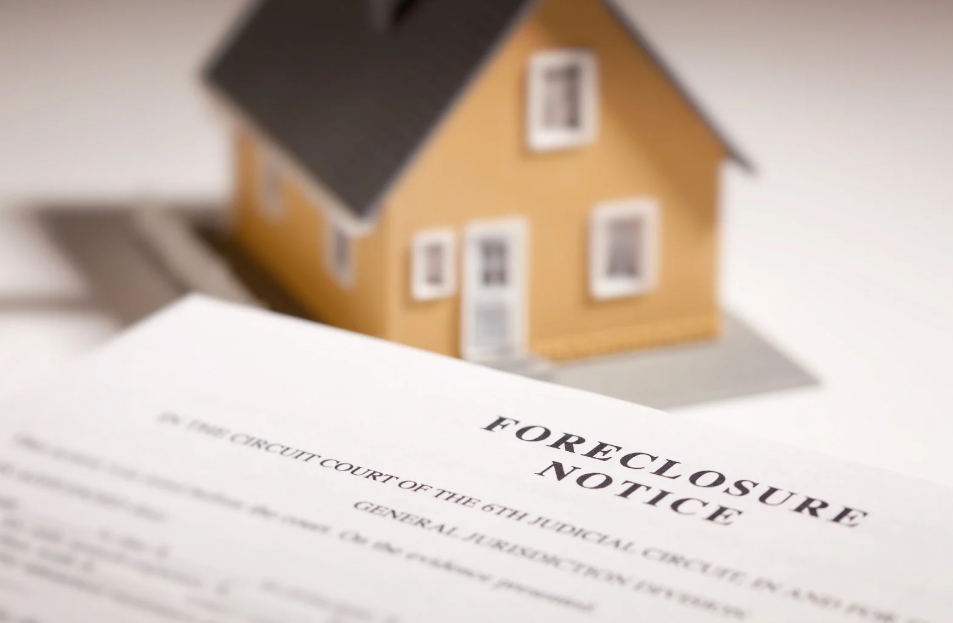 A model house is sitting on top of a foreclosure notice