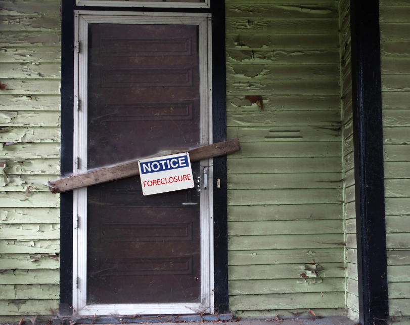 A broken screen door with a foreclosure notice sign on it