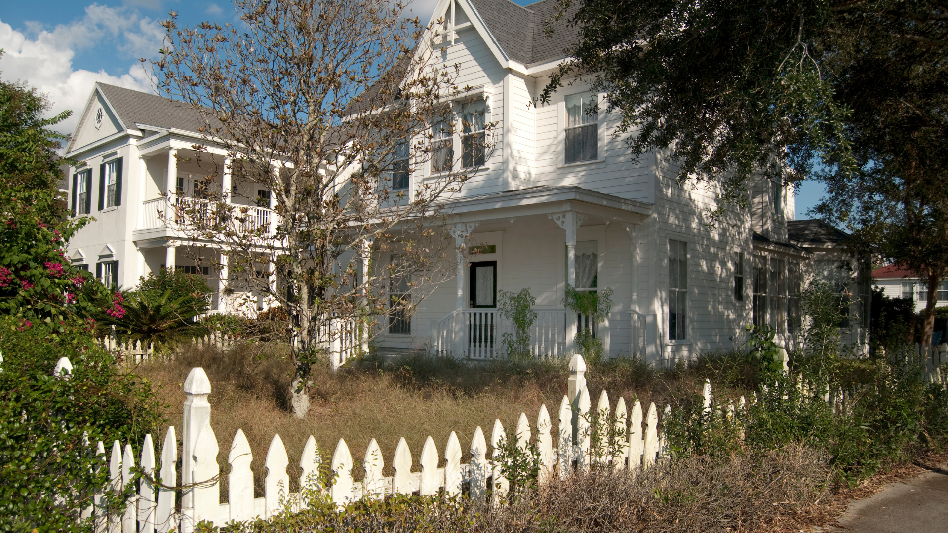 A white wauwatosa house with a white picket fence in front of it